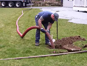 Septic pumping technician servicing a residential septic tank with a vacuum hose in Saint Petersburg, FL