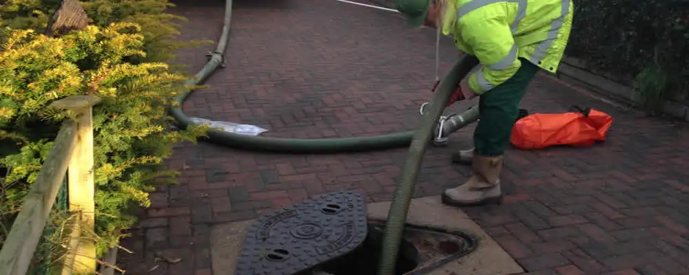 Septic tank cleaning technician servicing a septic tank with a vacuum hose in Saint Petersburg, FL