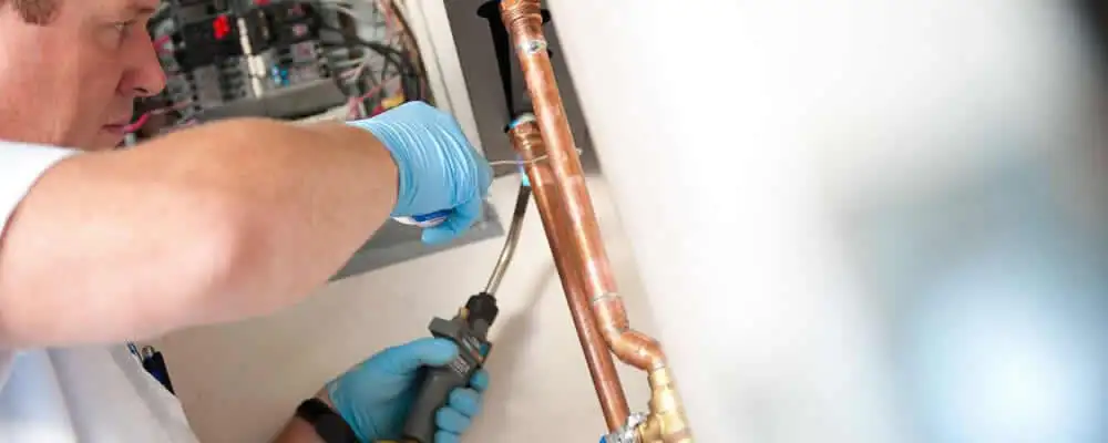 Water heater repair technician testing copper pipe connections and controls in Saint Petersburg, FL
